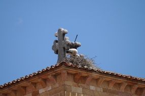 stork nest on the roof with a cross