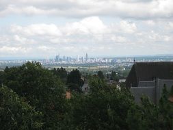 panoramic view of frankfurt behind green trees