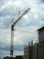 Construction crane and scaffolding in the background of a cloudy sky