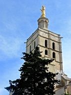 Tower of the church with the spire at blue sky background with white clouds