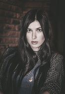 brunette with long hair on a background of a brick wall