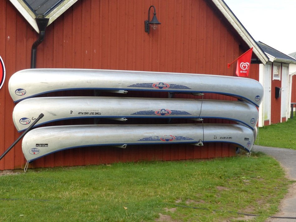 three canoes at wall of brown building