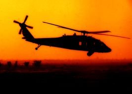 military helicopter against the orange sky