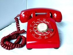 red old telephone on a white surface
