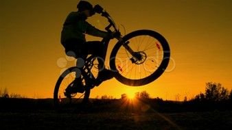 cyclist doing a stunt at sunset