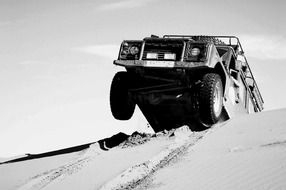 black and white image of a jeep on the dunes in the desert of Morocco