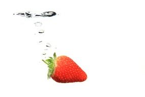 Strawberry falling in a spray of water