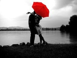 Black and white photo of the couple in love with the red umbrella