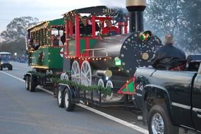 people in toy steam locomotive on wagon, Christmas Parade on road