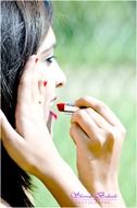 Girl paints her lips with red lipstick