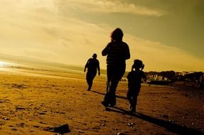 people walking on the beach at sunset