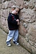 sad boy by the stone wall