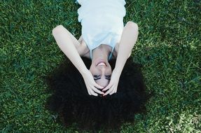 woman lying on young green grass in a park
