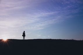 silhouette of a girl on a hill at sunset