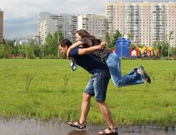 Men is helping woman to cross the puddle