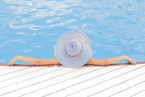 relaxing woman in wide hat in pool