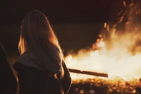 blonde woman looking at fire