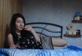 girl with black hair lies on the bed