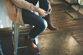 girl puts on boots with jeans