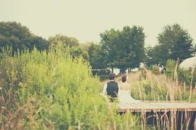 the bride and groom are sitting on a park bench