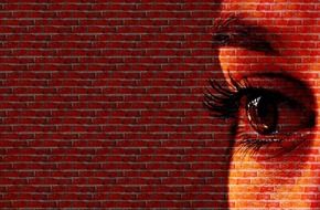 Drawing of woman face is on a brick wall