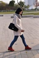 Asian woman walking in white coat