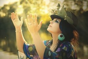 brunette woman in a hat decorated with flowers demonstrates the joy of life