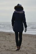 Woman is walking on a beach at winter