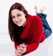 young woman in a red jumper naturally smiling and lying on a white background