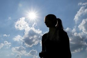 silhouette of a girl with a long tail against the blue sky