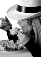 pretty blonde girl in hat eating pasta