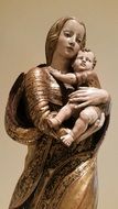 metal statue of a woman with a child near the wall