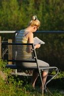 woman on a bench reading a newspaper