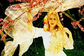 Beauty Blond girl standing near the Chery tree