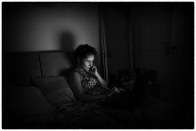 black and white photo of a woman with a laptop in the dark