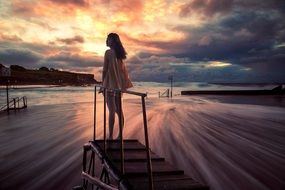 girl stands on the beach at sunset