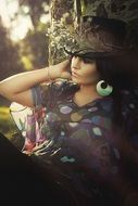 beautiful woman with black hair in a flowered hat on a background of nature