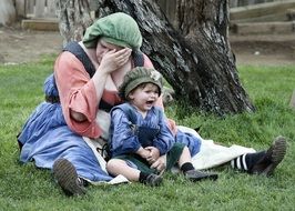 Photo of streesed mother with her baby dressed up in old fashioned clothes