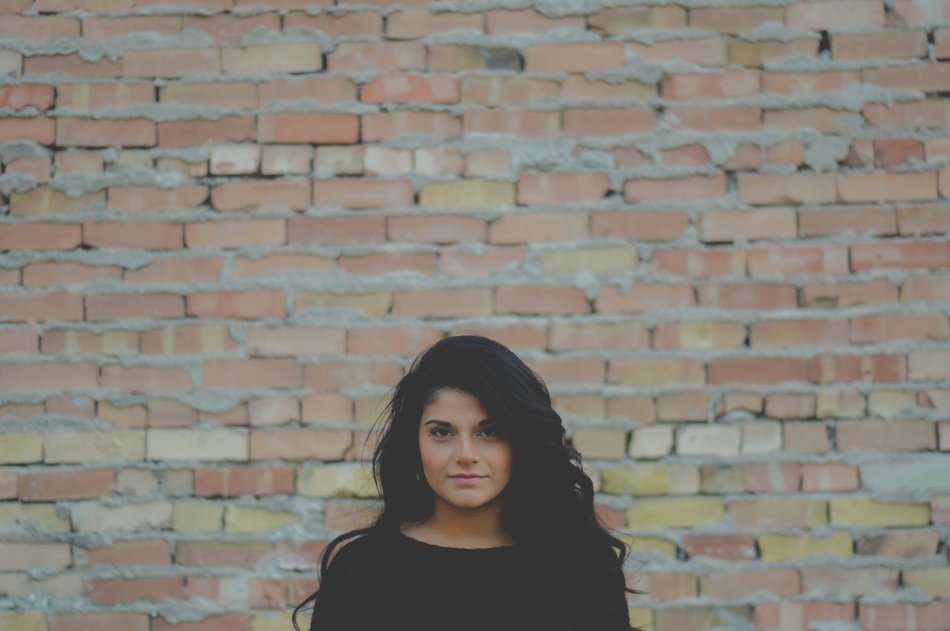Photo of byoung girl at the background of the brick wall