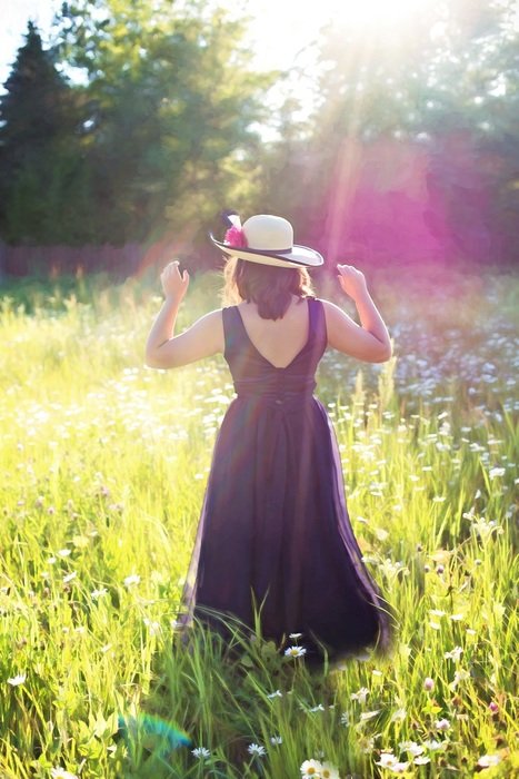 woman with hat on a meadow in sunbeams