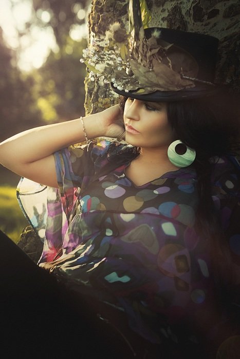 beautiful woman with black hair in a flowered hat on a background of nature
