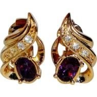 gold earrings with red stones on a black background