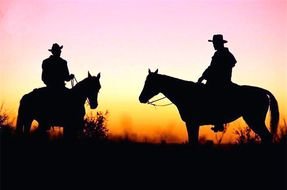 horse riders on a field at dusk