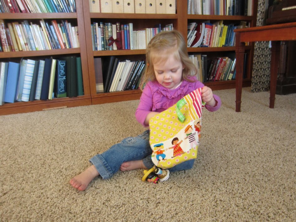 girl puts toys in a bag on the carpet in the room