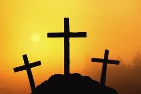 Three black Crosses on hill at orange sky