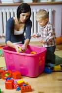 young mother with child boy in room among colorful toys