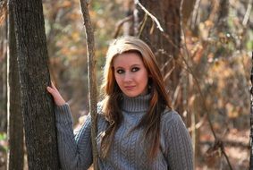 girl stands near a tree in the forest