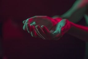 hands in colored lights on dark