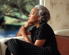 elderly black woman looks out the window