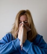 woman in a blue lab coat blowing his nose